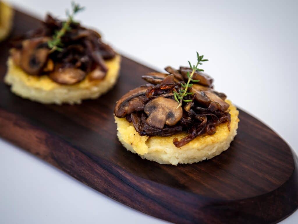 Une recette de petites bouchées de polenta et de champignons et oignons caramélisés. Une recette végétarienne, sans gluten et même végétalienne pour l'apéritif ! Idéale pour la saison des fêtes de fin d'année.