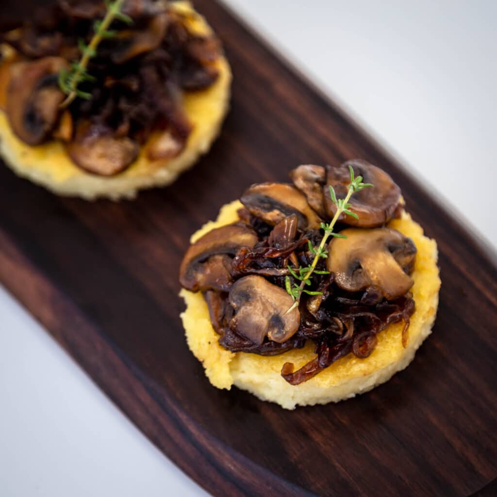 Une recette de petites bouchées de polenta et de champignons et oignons caramélisés. Une recette végétarienne, sans gluten et même végétalienne pour l'apéritif ! Idéale pour la saison des fêtes de fin d'année.