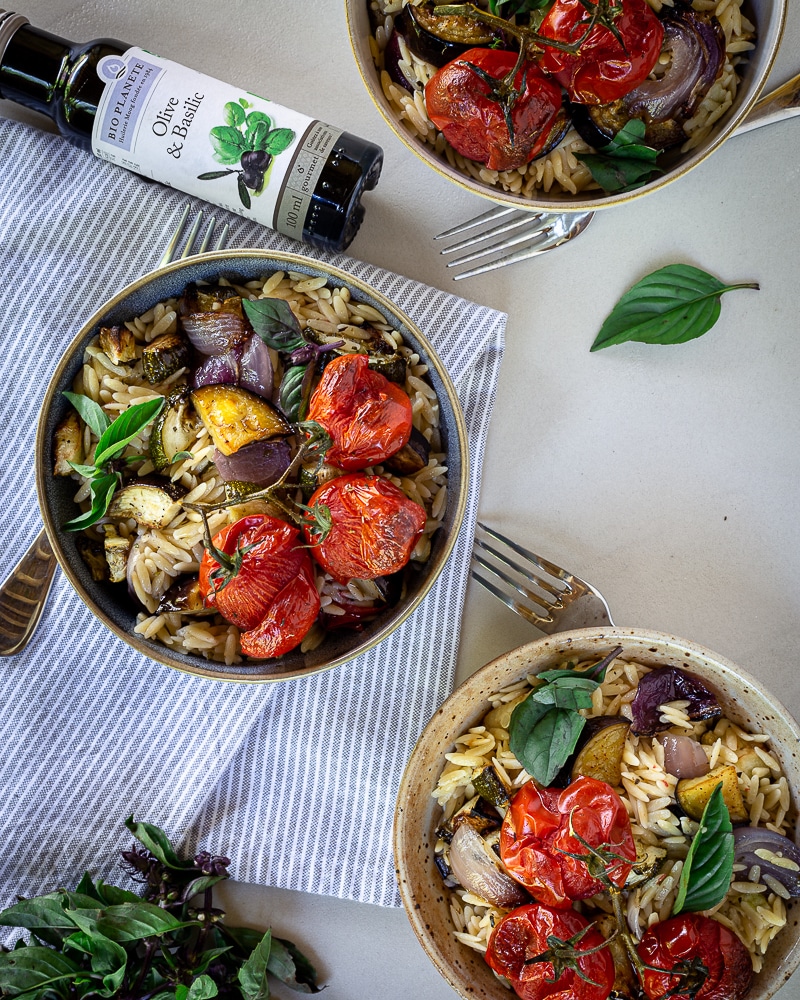 Salade aux Légumes d'Été et Petites Pâtes Orzo  Avez-vous déjà entendu parler des Orzos ? Ces petites pâtes en forme de grains de riz, qu’on trouve aussi sous le nom de Risoni ! En Grêce, on les utilise notamment pour faire du Youvetsi https://www.google.com/search?client=firefox-b-d&q=youvetsi mais c’est encore toute une autre histoire ! Un jour, promis, je ferai une recette de youvetsi végé ! Mais en attendant, quand Bio Planète nous a demandé de créer une recette avec leur nouvelle huile d’olive au basilic, je me suis dit qu’il nous fallait quelque chose de frais, et de méditerranéen, avec de bons légumes de saison ! https://www.greenweez.com/bio-planete-m12109   Il n’y a rien de compliqué dans cette recette, quelques légumes d’été rôtis à l’huile d’olive et au vinaigre, un peu d’ail, de l’huile au basilic et mes petites orzos ! Concernant les nouvelles huiles Bio Planète, je dois avouer que je n’ai pas tout à fait convaincue que j’allais aimer au premier abord. Vous me connaissez, j’aime faire les choses moi-même et surtout savoir ce qu’il y a dans ce que je mange !  J’avais d’ailleurs fait un recette d’huile parfumée au basilic maison pour le blog que vous pouvez retrouver ici (et qui est très bonne ;)).  C’est pourquoi, je réservais vraiment mon jugement. Mais, je dois dire que cette fois-ci j’approuve complètement. J’ai testé l’huile d’olive au basilic, celle à l’ail et celle au citron, et j’ai été impressionnée par la puissance des saveurs, et la compo, qui est nickel (c’est-à-dire qu’il n’y a rien d’autre que l’huile et le basilic ou l’ail ou le citron).  Si vous n’avez pas envie de vous prendre la tête à faire vos propres huiles parfumées, alors celles-ci sont une très bonne alternative !  Cette recette a été créée dans le cadre d’un partenariat rémunéré et vous pouvez bénéficier d’un code promo de 10% sur les produits BIO PLANÈTE suivants : Huile olive & ail 100ml, Huile olive & basilic 100ml , Huile d'olive O'citron 100ml avec le code BIOPLANETE. Offre valable jusqu'au 31/07/2020, 50€ de remise max.     pour 4 personnes  1 courgette bio pour pouvoir garder la peau (environ 250g) 1 aubergine bio pour pouvoir garder la peau (environ 250g) 1 oignon rouge (environ 100g) 1 tête d’ail 12 tomates cerises (environ 300g) 2 c-à-s d’huile d’olive 2 c-à-s de vinaigre de vin sel, poivre 1 c-à-c d’origan séché (ou de thym) 1 c-à-c d’ail en poudre 200g de orzo (poids cru) 2 c-à-s d’huile d’olive au basilic Bio Planète  Préchauffer le four à 210 degrés. Préparer une plaque de cuisson en la couvrant de papier cuisson. Laver (et éplucher si nécessaire) puis couper la courgette, l’aubergine dans le sens de la longueur, puis en rondelles. Eplucher et émincer l’oignon en grosses rondelles. Enlever les couches supérieures de peau de la tête d’ail, sans l'éplucher complètement. Puis coupez le dessus de la tête pour que toutes les gousses soient ouvertes sur le dessus. Disposez les légumes coupés et les tomates cerises entières sur la plaque, puis versez l’huile, le vinaigre, le sel, le poivre, l’origan et l’ail séché par dessus et mélangez pour tout bien repartir. Etaler les légumes au maximum sur la plaque et enfourner à mi-hauteur 30min. Pendant ce temps, faites cuire les orzo en suivant les indications du paquet. Attention à ne pas les cuire trop longtemps,  ça devient vite trop mollasson sinon.  Une fois que les légumes sont cuits, mélangez les avec les orzo et deux belles cuillères à soupe d’huile d’olive au basilic ! Laissez refroidir et servez tiède ou froid !