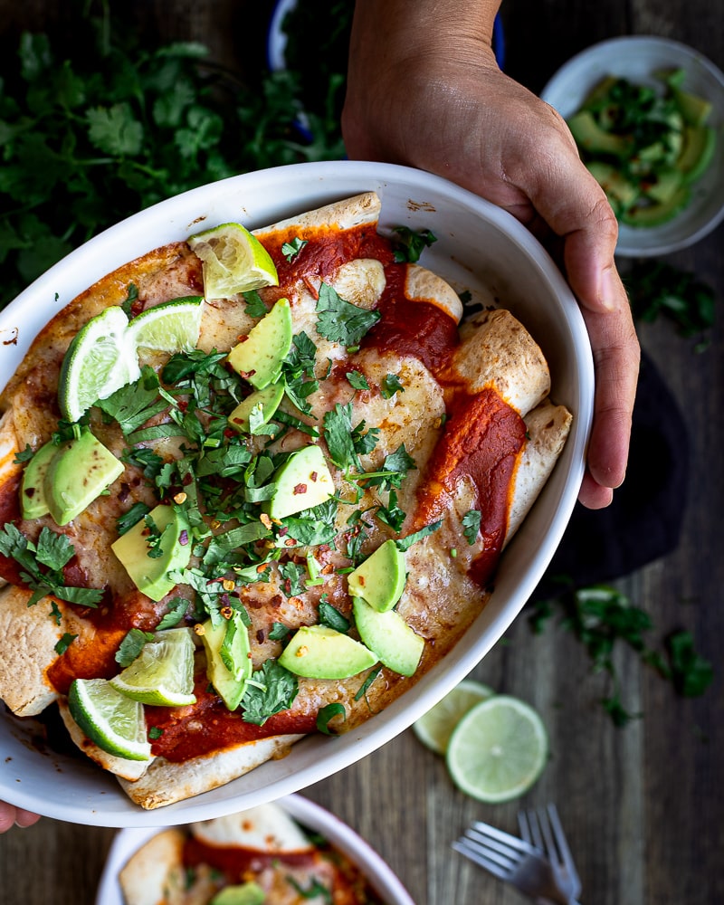 Enchiladas Végétariennes aux Haricots Rouges, Maïs et Poivrons Je vous présente ma dernière petite découverte bien sympa ! Ou plutôt re-découverte ! Les enchiladas ! J’adore la cuisine TexMex et la cuisine sud américaine ! Et même si je ne suis vraiment pas une spécialiste, j’adore m'inspirer des saveurs latinos :) Et puis, j’ai toujours Daniela pour valider. Avec son sang colombien, elle a le pouvoir de validation absolu sur toutes mes tentatives culinaires sud américaines ! Je suis assez fière d’ailleurs, parce qu’après de savants ajustements d’assaisonnement, elle a validé mon aji colombien (et même si les photos sont assez affreuses, c’est une grosse tuerie !). Elle a aussi validé mes quesadillas végétariennes, et maintenant, elle a validé mes enchiladas ! Grosse fierté ! La recette risque de vous paraître complexe, mais en vrai pas du tout ! Le secret est dans la sauce. On n’utilise pas une sauce tomate simple (c’est-à-dire à base de tomates concassées) comme on le fait dans la cuisine méditerranéenne, mais à la place, c’est une sauce à base de concentré de tomate très chargée en épices. Au niveau de la préparation, ça ressemble plus aux étapes de la béchamel d’ailleurs. On commence par faire une sorte de “roux” avec de l’huile, de la farine et les épices, et ensuite on ajoute le concentré de tomate et le bouillon jusqu’à obtenir un consistance presque crémeuse ! C’est vraiment très simple à réaliser ! Et surtout, il ne faut pas avoir peur d’y aller franchement avec les épices ! Et une fois que cette sauce est faite, c’est dans la poche. On n’a plus qu’à préparer une garniture de haricots rouges, maïs et poivron, ajouter un peu de cheddar, rouler tout ça dans des tortillas et hop au four ! Easy like one, two, three :) ! prep 1h cuisson 20min Pour 8 enchiladas (4 personnes) Pour la sauce enchiladas 500ml d’eau 1 bouillon cube de légumes 40g de farine 1 c-à-c de cumin en poudre ½ c-à-c de chili en poudre ½ c-à-c de paprika fumé ¼ c-à-c d’origan séché 1 c-à-c d’ail en poudre sel 140g de concentré de tomate (ne pas utiliser de sauce tomate ou de tomates concassées) 3 c-à-s d’huile végétale 1 c-à-c de vinaigre de cidre (ou de vinaigre blanc) Pour la garniture 400g de haricots rouges cuits* (ou en conserve) 3 c-à-s d’huile végétale 1 oignon rouge en fines lamelles ½ c-à-c de paprika fumé ½ c-à-c de paprika doux 2 c-à-c de cumin en poudre ½ c-à-c de chili en poudre (plus ou moins au goût) 1 poivron rouge épépiné et coupé en fines lamelles 3 gousses d’ail pressées 300g de maïs en conserve ou surgelés 1 poignée d’épinards frais ou surgelés la moitié de la sauce préalablement préparée Pour le montage 8 tortillas de blé 300g de cheddar râpé (un mix cheddar emmental et/ou mozza fait très bien l’affaire aussi) 1 botte de coriandre hachée (feuilles et tiges) 2 avocats coupés en morceaux 1 citron vert coupé en morceau Pour la sauce Faire bouillir l’eau avec le bouillon cube jusqu’à ce que ce dernier soit complètement dissout. Réserver. Préparer la farine, les épices et le sel dans un bol et réserver. C’est important de tout préparer en avance car ensuite la sauce est rapide à faire et vous n”aurez pas le temps de mesurer les quantités. Ouvrir la (ou les) conserve(s) de concentré de tomate. Dans une casserole, faire chauffer à feu moyen-fort l’huile végétale, puis y verser la mix de farine/épices et mélanger avec un fouet. Vous devriez obtenir un pâte très aromatique (qui fait un peu penser à un roux comme pour la béchamel). Ajouter le concentré de tomate, toujours à feu moyen-fort et battre avec le fouet pour obtenir une pâte. Ajouter ensuite petit à petit (en 5 ou 6 fois) le bouillon de légumes tout en fouettant. La sauce devrait épaissir rapidement. Éteindre le feu lorsque la surface de la sauce offre un peu de résistance. Tout ce processus dure environ 5 à 7 min. Réserver. La sauce risque de figer, mais ce n’est pas grave, il suffit de la mélanger un peu pour qu’elle retrouve son onctuosité. Vous pouvez la préparer à l’avance et la conserver au frais jusqu'à 3 jours. Pour la garniture des enchiladas Dans une poêle à bords hauts, faire chauffer l’huile à feu moyen. Ajouter l’oignon émincé, et les épices et bien mélanger. Cuire environ 5min, jusqu’à ce que les oignons commencent à devenir translucides. Ajouter le poivron émincé et laisser cuire encore 10min en remuant régulièrement. Ajouter les haricots, le maïs et les épinards et laisser cuire encore 5min, puis verser les 2/3 de la sauce à enchiladas et bien mélanger. éteindre le feu et réserver. Pour le montage Préchauffer le four à 180 degrés. Prévoir un plat qui va au four et qui est suffisamment grand pour accueillir 8 tortillas roulées. Dans chaque tortillas : Mettre environ 2 à 3 c-à-s de garniture, et une c-à-s de cheddar rapé (gardez environ la moitié du cheddar pour plus tard). Rouler la tortilla et la poser dans le plat (avec l'ouverture vers le bas) Disposer les tortillas les unes à côté des autres. Couvrir avec la fin de la sauce en laisser les extrémités des enchiladas découvertes pour qu’elles grillent et croustillent. Couvrir la sauce avec la fin du cheddar. Enfourner à mi-hauteur pour 15-20min. Vous pouvez mettre le mode grill pour les dernières minutes pour faire griller le fromage. Pendant ce temps, couper les avocats et le citron et hacher la coriandre. Sortir du four et mettre l’avocat, le citron et la coriandre par dessus. Servir immédiatement. Les enchiladas ne se conservent pas bien, elles s’imbibent de sauce et se détrempent. Si vous souhaitez les préparer à l’avance, il est préférable de tout préparer mais de ne faire la partie “montage” qu’au dernier moment. *cuisson des haricots rouges secs : Pour obtenir 400g de haricots rouges cuits, il faut compter environ 130g de haricots secs. Cela dit, je fais toujours une quantité plus importante que je congèle ensuite ! 1/ les rincer à l’eau clair, puis les mettre à tremper (4h avec une c-à-s de bicarbonate, ou toute la nuit à l’eau claire). Il vaut mieux les faire tremper trop longtemps plutôt que pas assez car sinon ils seront difficiles à cuire et indigestes. 2/ jeter l’eau de trempage 3/ les rincer de nouveau 4/ les transférer dans une grande casserole et recouvrir de 2 ou 3cm d’eau. Porter à ébullition et laisser cuire 1h environ (25 à 30min à la cocotte devraient suffir).