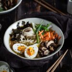 Je vous propose un Ramen Végétarien au Miso et Tahini ! J’ai utilisé une base de gingembre, ail et tahini pour apporter du goût et de la richesse au bouillon. Bien sûr, de la feuille de nori et du miso blanc (à ajouter en fin de cuisson). Et après, une touche de vinaigre de riz et d’huile de sésame pour perfectionner le goût ! Puis, de toute façon, au-delà du bouillon, le kiffe est dans la garniture. Vous n’êtes pas d’accord ? Des œufs mollets, des shiitakés grillés à l’ail, de la cébette ! Miam miam miam