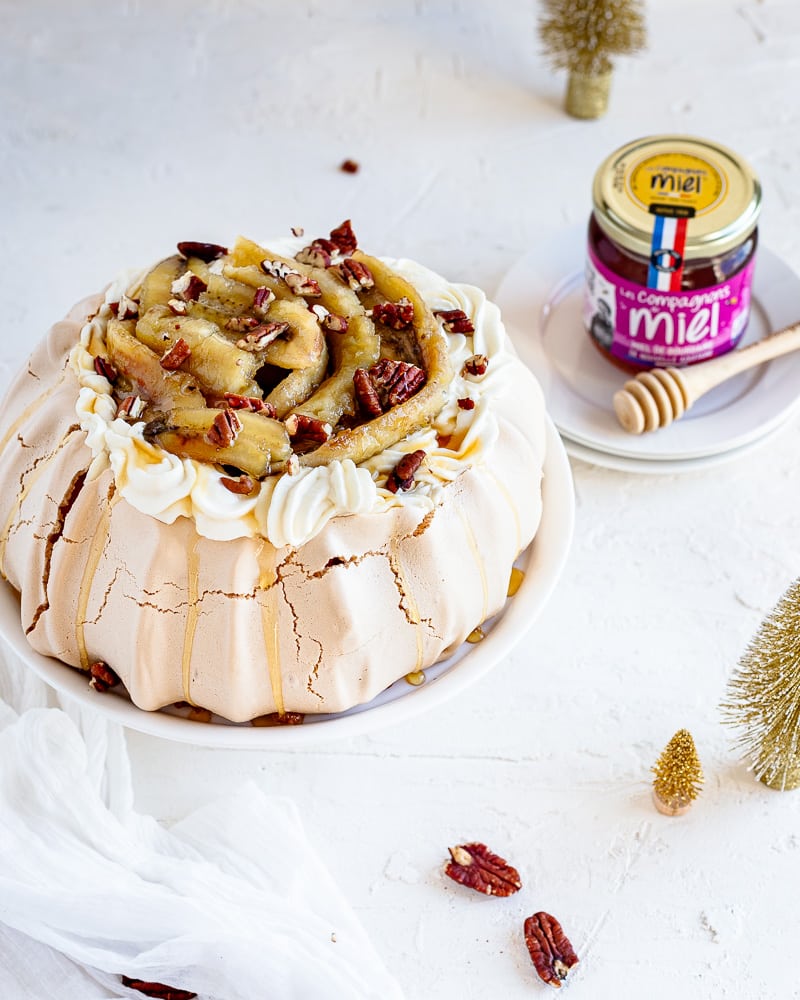 Une Pavlova Bananes Flambées gourmande à souhait et idéale comme dessert de Noël. Une meringue croquante à l'extérieur et comme un marshmallow à l'intérieur, le tout surmontée d'une chantilly au miel de Bourdaine et d'une pluie de noix de pécan !