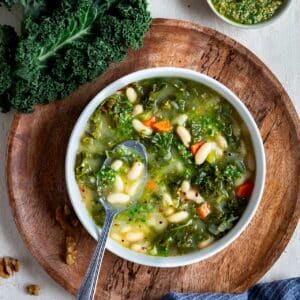 Soupe crémeuse aux haricots blancs et kale, vegan, nourrissante et riche en protéines. À servir avec une picada noix kale pour plus de caractère.